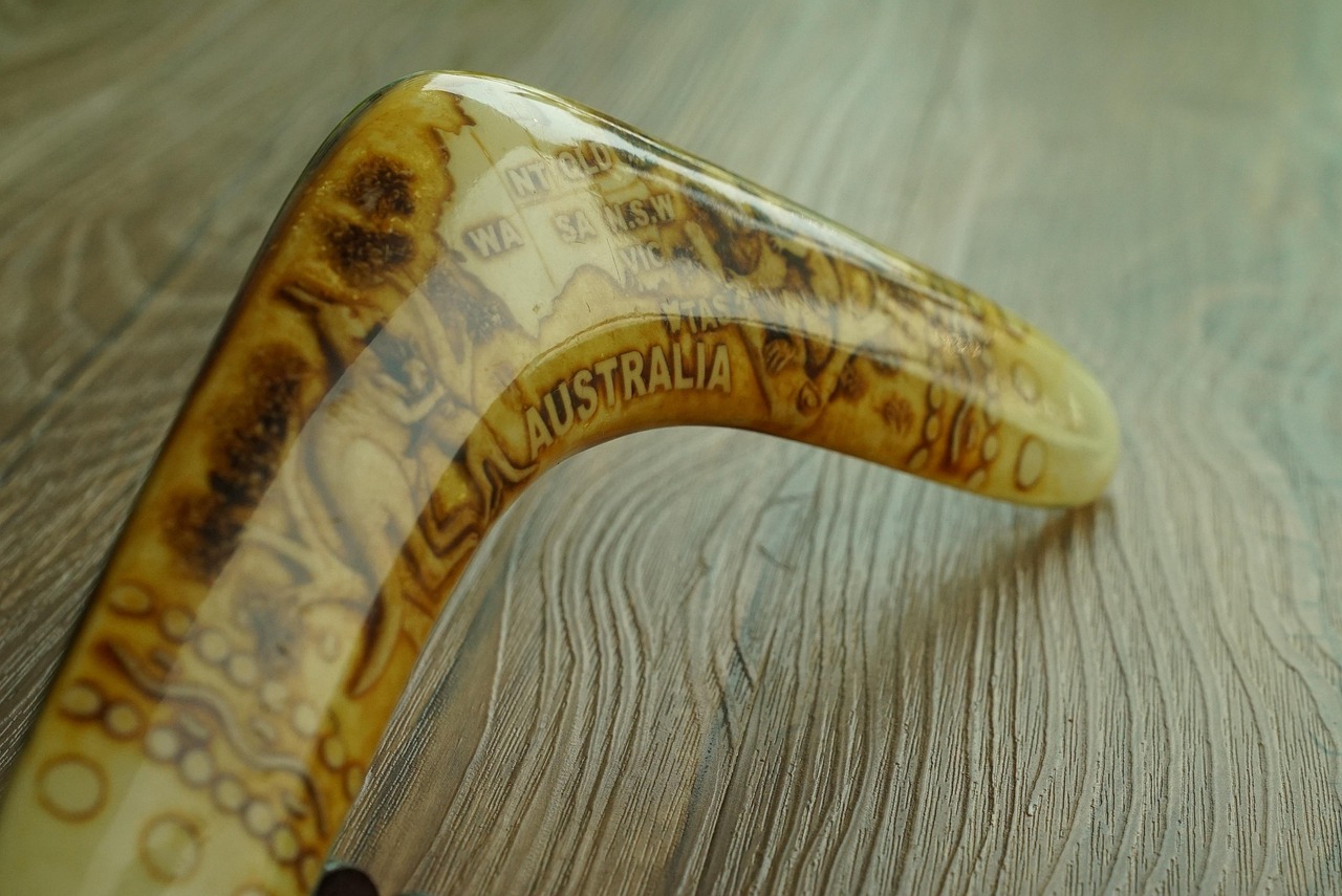 A wooden boomerang with 'Australia' written on it sits on a wooden table.