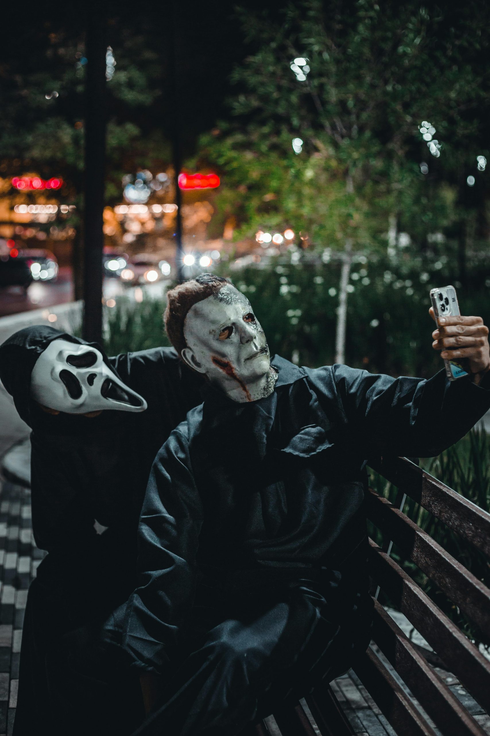 Two masked men pose in a scream mask and Mike Myers mask for halloween.